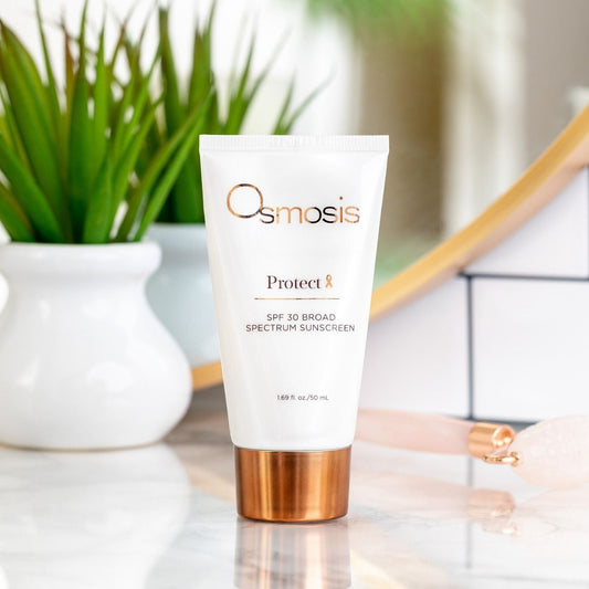 Tube of Osmosis Protect spf displayed in white bathroom with plant and mirror in the background