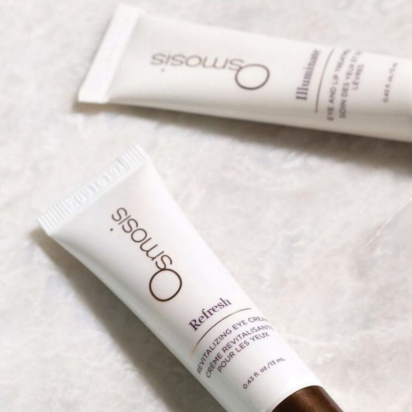 two tubes of osmosis beauty skincare laying down displayed on counter