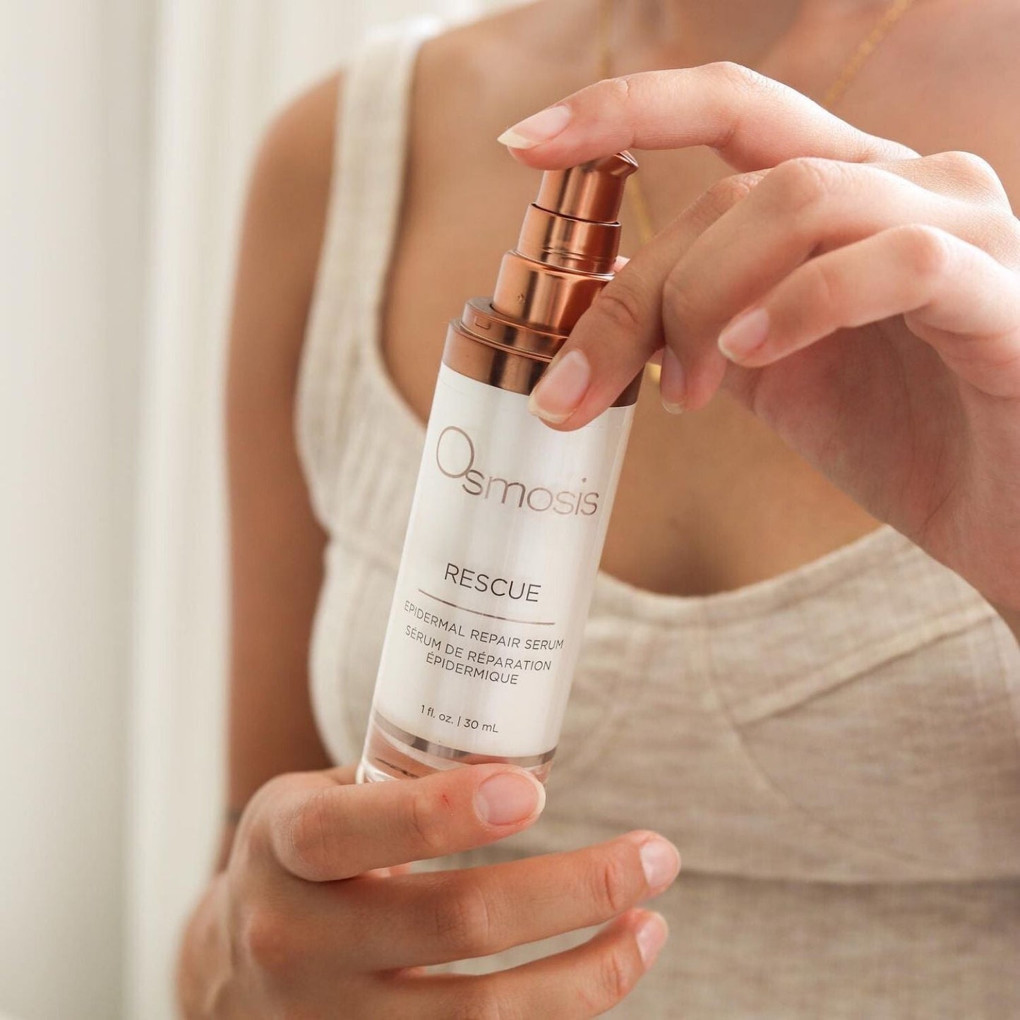 Model with pretty hands is holding a bottle with a pump of rescue serum