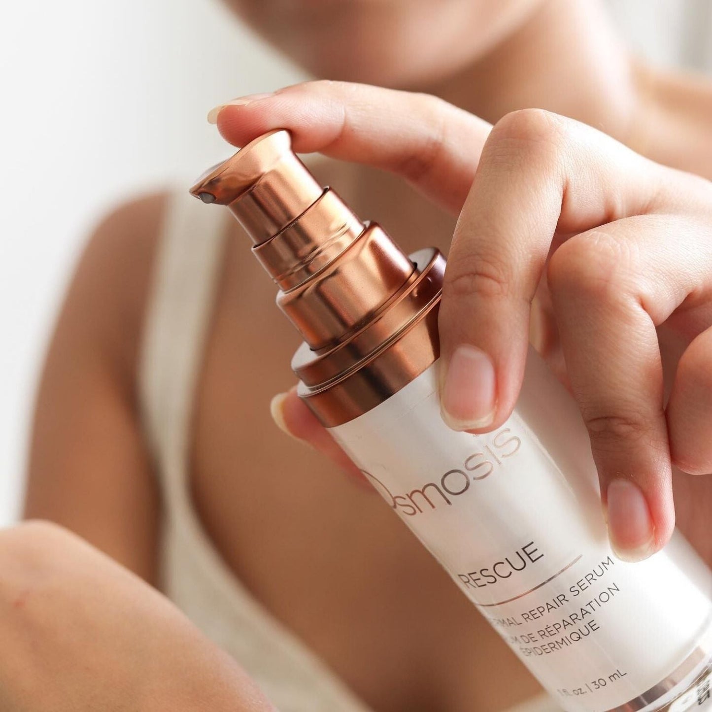 Close up of a models hand holding a bottle of rescue serum by osmosis