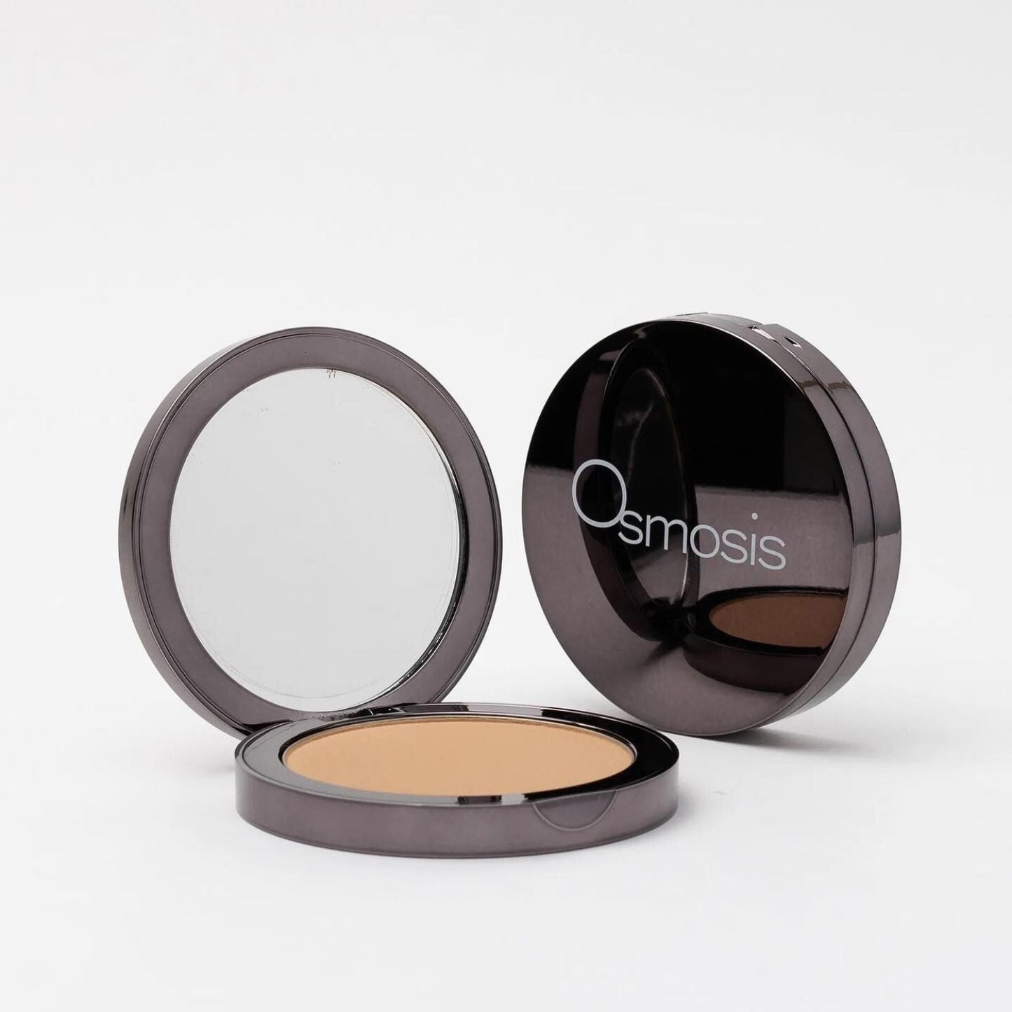 opened compact next to closed compact of pressed base powder on white background