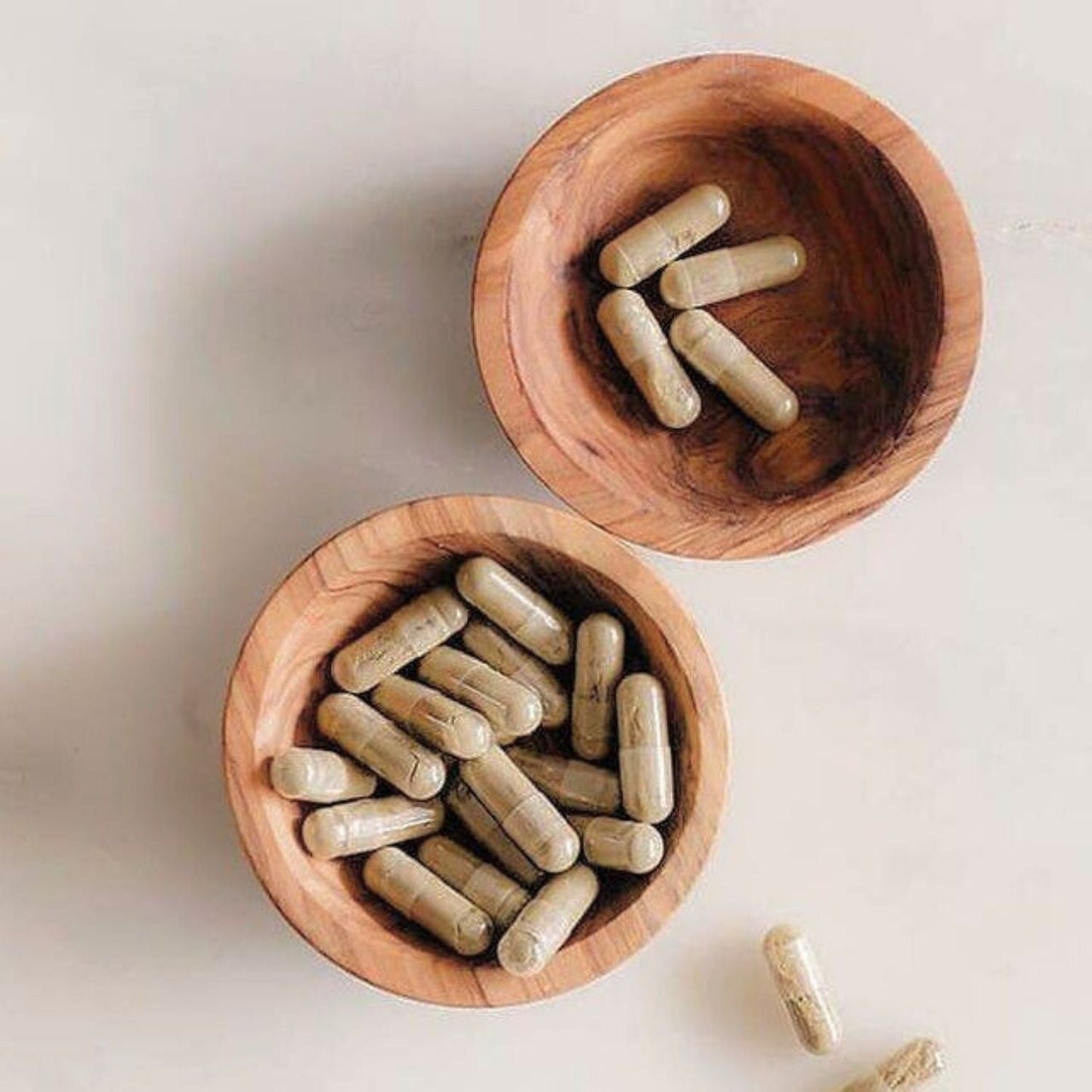 two wooden bowls holding supplements capsules by osmosis