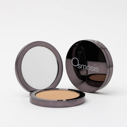 opened compact next to closed compact of pressed base powder on white background